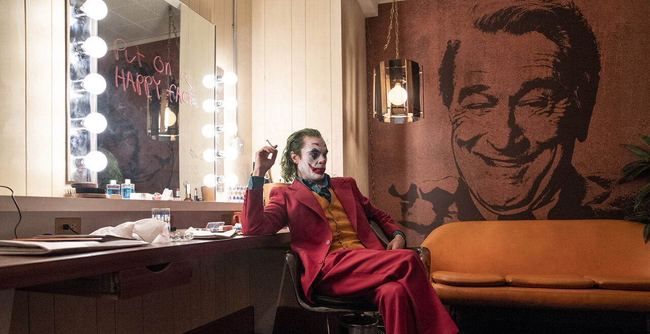 Joker_Still - <strong>Der Clown und der Talkmaster</strong><br />
Joaquin Phoenix in der Titelrolle des Joker Arthur Fleck, Robert De Niro als Late-Night-Talker Murray Franklin (auf der Tapete). - © Warner