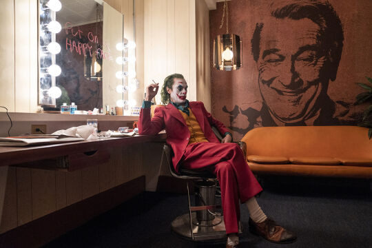 Joker_Still - <strong>Der Clown und der Talkmaster</strong><br />
Joaquin Phoenix in der Titelrolle des Joker Arthur Fleck, Robert De Niro als Late-Night-Talker Murray Franklin (auf der Tapete). - © Warner