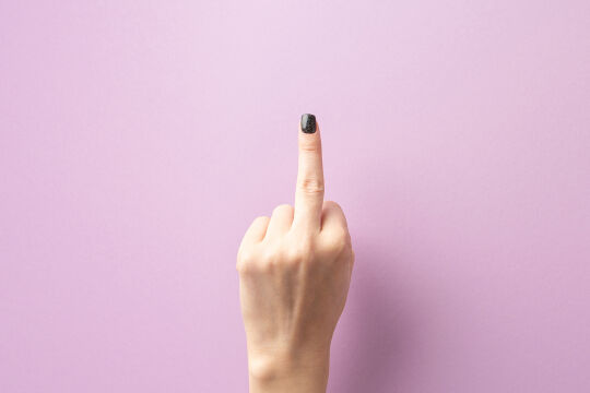 Der ausgestreckte Mittelfinger - ein universelles Zeichen der Unhöflichkeit - Das Bild zeigt eine Hand vor einem pinken Hintergrund mit einem ausgestreckten Mittelfinger.&nbsp; - © iStock/InspirationGP