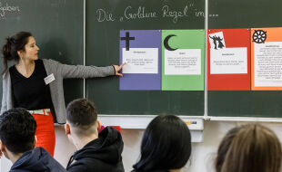 Interreligiöser Religionsunterricht - Eine Religionslehrerin zeigt Jugendlichen an der Tafel Zugänge in Christentum, Islam und Buddhismus zur „Goldenen Regel“ - © picturedesk.com / dpa / Markus Scholz