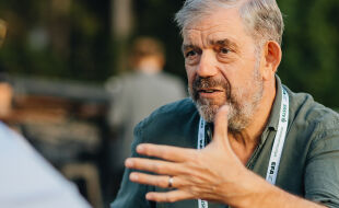 Der Philosoph Tim Crane im Interview mit Philipp Axmann in Alpbach 2025 - Ein Mann mit einem grauen Bart trägt ein dunkelgrünes Hemd und spricht mit einem jungen Mann in einem hellblauen Hemd - © Foto: Michael Kiran Huber
