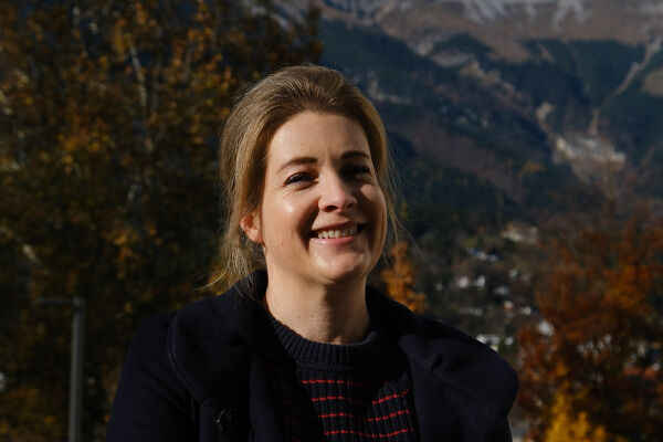 Marie-Luisa Frick, Philosophin Uni Innsbruck - Eine Frau steht auf dem Campus der Universität vor Bäumen, im Hintergrund sind Berge zu sehen. - © Foto: Jenni Zeller