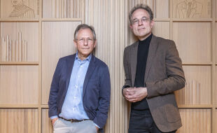 Doron Rabinovici und Jan-Heiner Tück - Zwei Männer stehen vor einem hölzernen Bücherregal mit mehreren Fächern, beide tragen Sakko und Hemd, einer in Blau, der andere in Braun. - © Foto: Carola Frank
