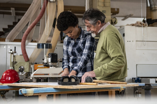 Boomer und GenZ am Arbeitsplatz - Ein älterer Herr und eine jüngere Frau beim gemeinsamen Handwerken - © Getty Images