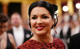 Anna Netrebko - Anne Netrebko in rotem, mit Perlen und Schmucksteinen besetztem Abendkleid mit hochgestecktem Haar und roten Ohrringen in einem festlich beleuchteten Raum. - © Foto: APA / Georg Hochmut