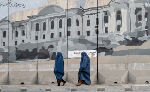 Frauen in Afghanistan - Zwei Frauen in blauen Burkas gehen in Afghanistan an einer Wand mit einem großflächigen Graffiti eines Gebäudes vorbei. - © Foto: APA / AFP / Wakil Kohsar