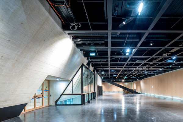 Wien Museum - Großer moderner Innenraum mit sichtbaren Betonstrukturen, Glasfronten und offenem Deckenraster mit Beleuchtung - © Foto: Kollektiv Fischka