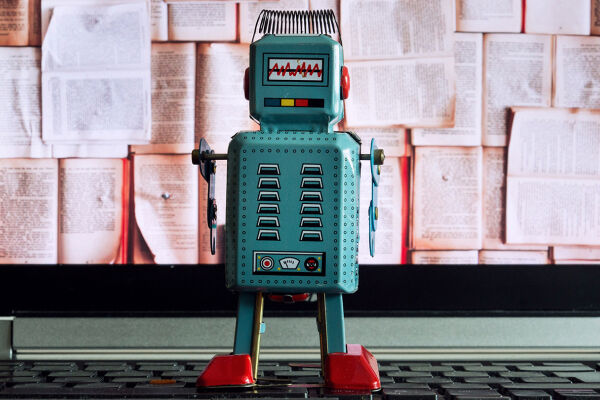 Roboter im Klassenzimmer - Das Foto zeigt einen Miniaturroboter vor einem Bildschirm mit vielen Buchseiten. - © Adobe Stock / josefkubes