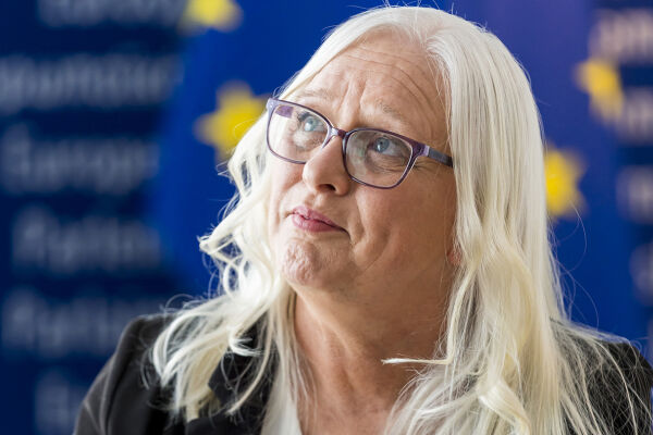 Jackie Fox spricht über Coco's Law - Das Foto zeigt Jackie Fox mit Brille und blonden, längeren Haaren vor einer EU-Flagge und blauem Hintergrund. - © European Union 2026 - Source : EP