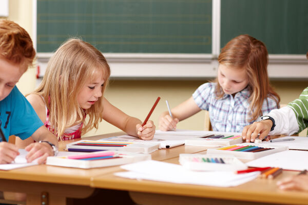 Schulklasse - Das Foto zeigt vier Schülerinnen und Schüler im Volksschulalter beim Zeichnen in einem Klassenraum. - © Adobe Stock / Christian Schwier