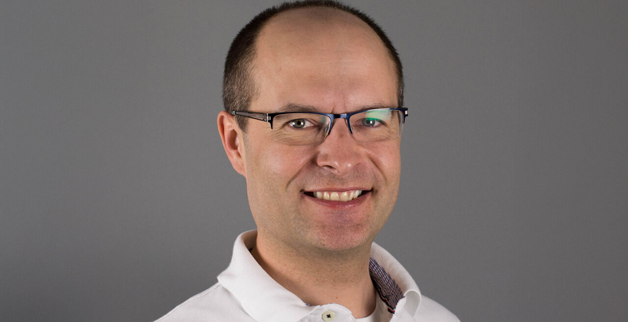 Gerold Muhri, Palliativmediziner, Elisabethinen - Das Porträtfoto zeigt Gerold Muhri mit Brille und in weißem Hemd vor braun-grauem Hintergrund. - © KHE Graz