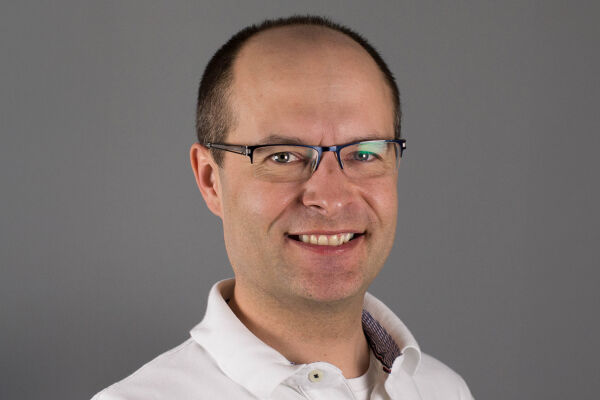 Gerold Muhri, Palliativmediziner, Elisabethinen - Das Porträtfoto zeigt Gerold Muhri mit Brille und in weißem Hemd vor braun-grauem Hintergrund. - © KHE Graz