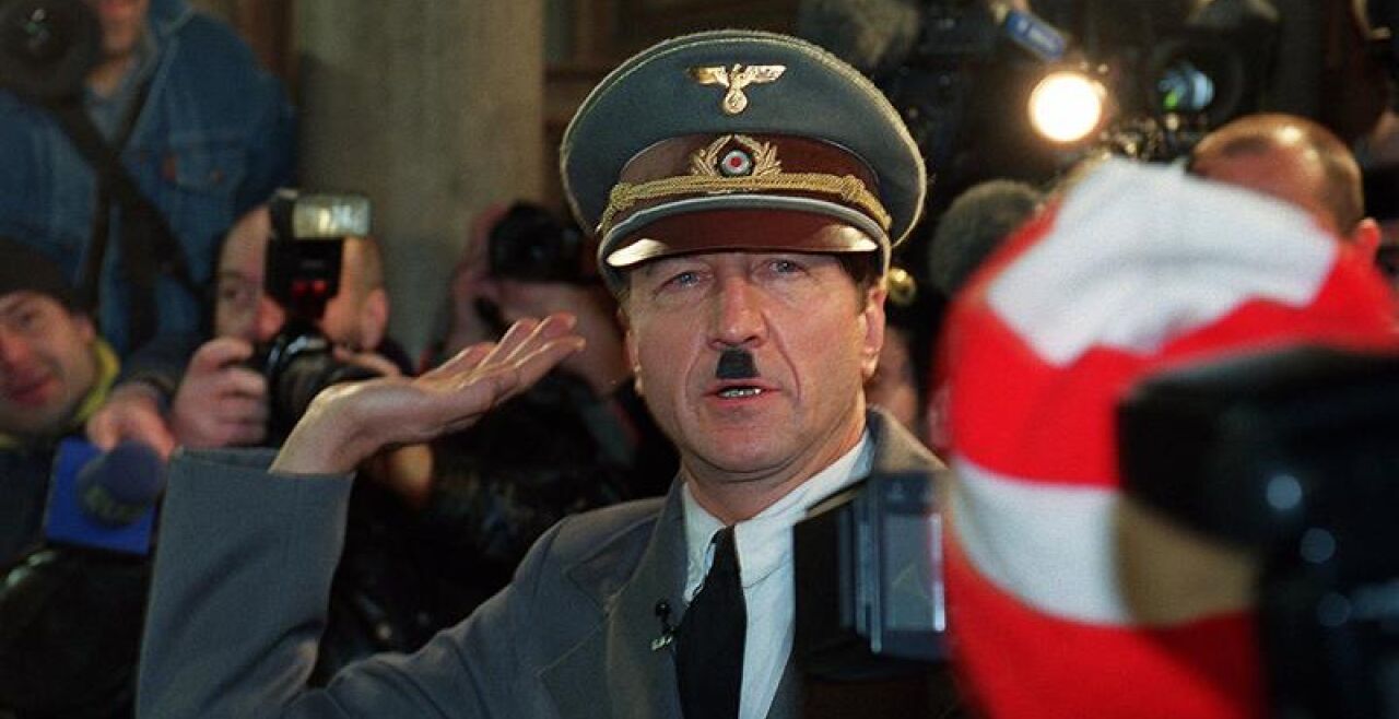 Er ist wieder da! - Opernballprotest im Jahr 2000 - Im Jahr 2000 schaffte es der Protest gegen die kurz davor angelobte schwarz-blaue Regierung bis in die Wiener Staatsoper. Der Kabarettist und Schauspieler Hubsi Kramar lässt sich als täuschend echter Adolf Hitler in einem weißen Rolls-Royce zum Opernball bringen. Er schafft es bis zur Feststiege, bevor ihn die Polizei festnimmt. - © APA-Images / Alexander Tuma