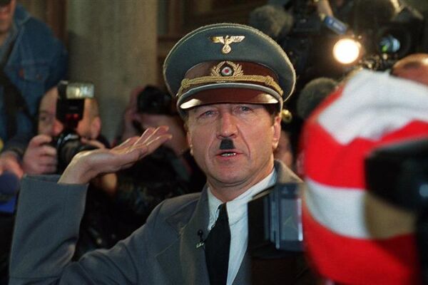Er ist wieder da! - Opernballprotest im Jahr 2000 - Im Jahr 2000 schaffte es der Protest gegen die kurz davor angelobte schwarz-blaue Regierung bis in die Wiener Staatsoper. Der Kabarettist und Schauspieler Hubsi Kramar lässt sich als täuschend echter Adolf Hitler in einem weißen Rolls-Royce zum Opernball bringen. Er schafft es bis zur Feststiege, bevor ihn die Polizei festnimmt. - © APA-Images / Alexander Tuma