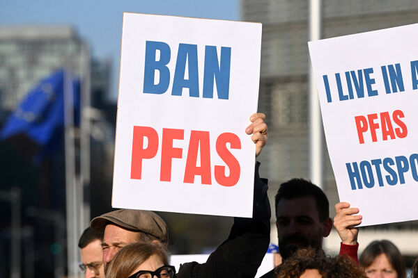 PFAS-Opfer Demonstration Bürgerprotest - Menschen halten Schilder mit den Aufschriften 'BAN PFAS' und 'I LIVE IN A PFAS HOTSPOT' bei einer Demonstration im Freien - © Foto: APA / AFP / Nicolas Tucat